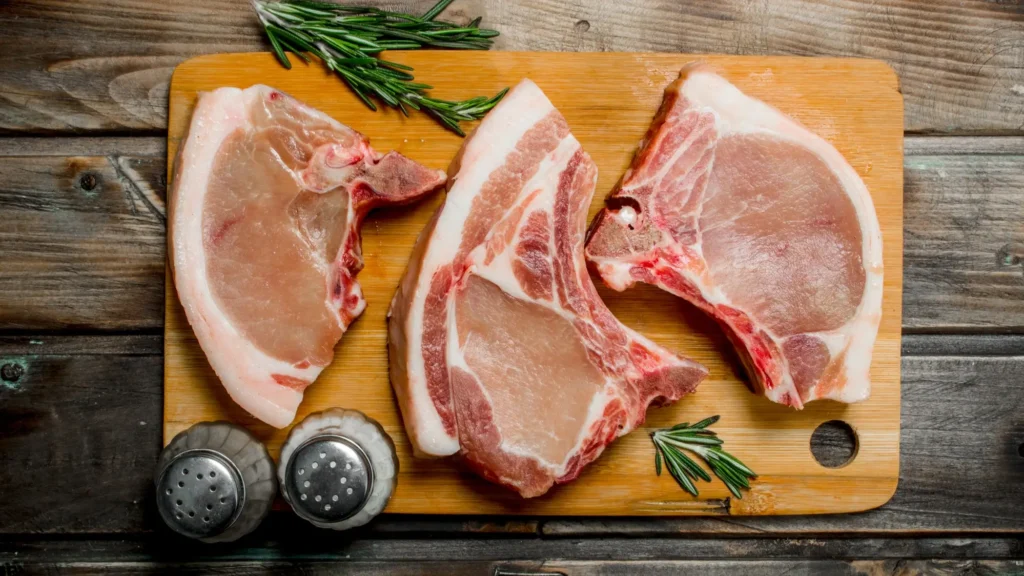 ثلاث قطع من لحم الخنزير النيء على المنضدة