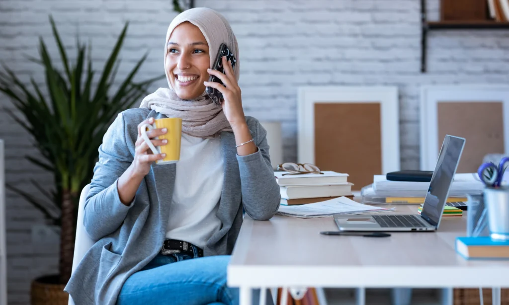 فتاة تتحدث بالهاتف أثناء احتسائها لمشروب مفيد للأحبال الصوتية